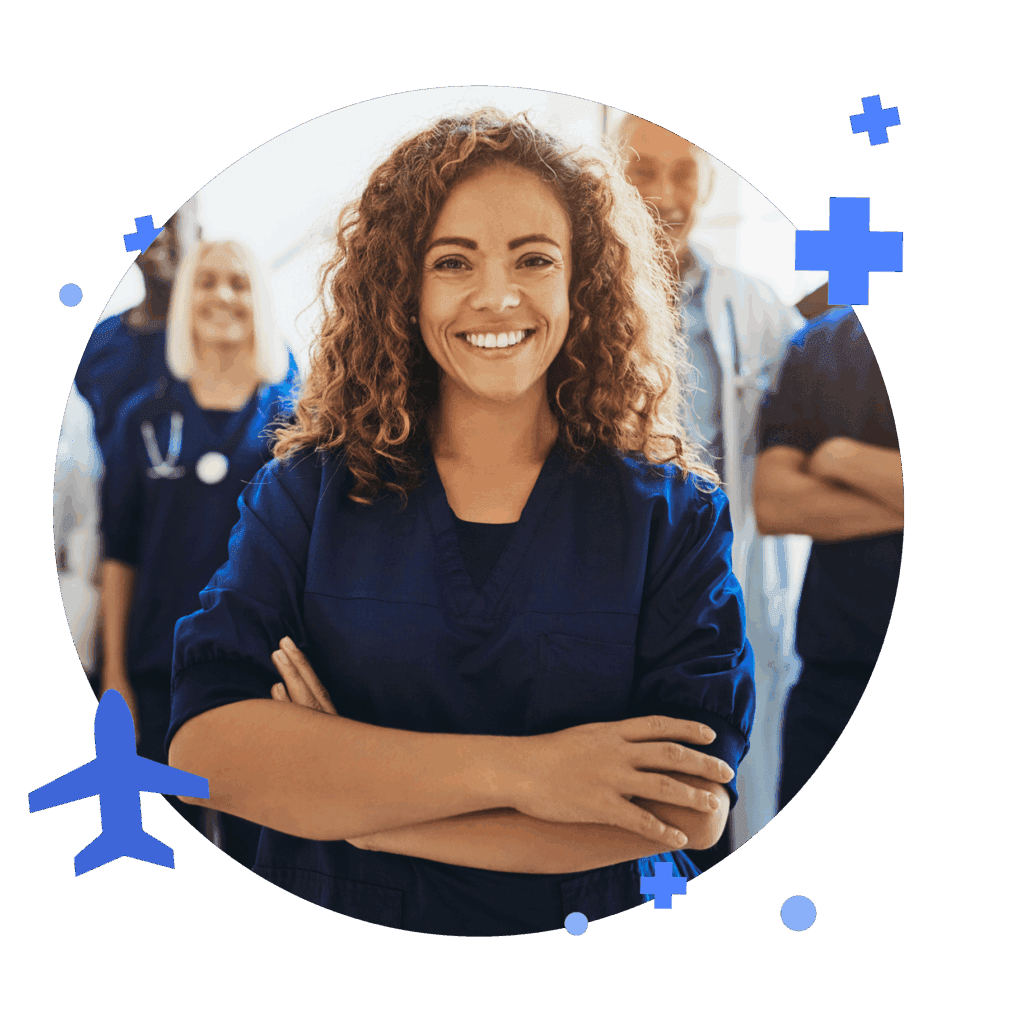 Smiling female healthcare professional in blue scrubs stands confidently with her arms crossed, surrounded by colleagues. Represents teamwork in healthcare.